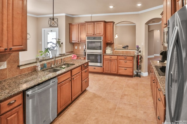 kitchen with appliances with stainless steel finishes, decorative backsplash, sink, and hanging light fixtures