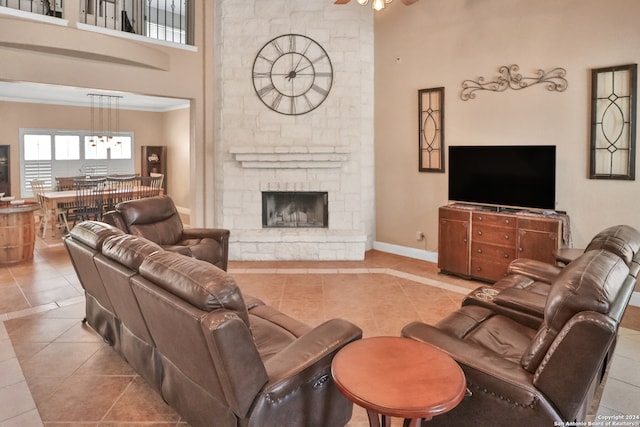 tiled living room featuring ornamental molding, a high ceiling, a fireplace, and ceiling fan