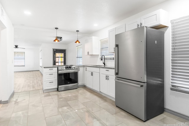 kitchen with light stone countertops, stainless steel appliances, kitchen peninsula, hanging light fixtures, and white cabinets