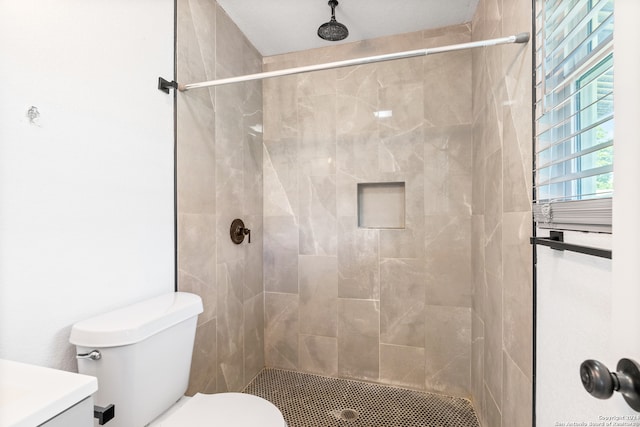 bathroom featuring a tile shower, vanity, and toilet