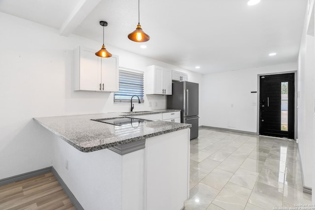 214 Oriole, San Antonio, TX 78228 - kitchen with light stone countertops, a sink, black electric cooktop, freestanding refrigerator, and white cabinetry