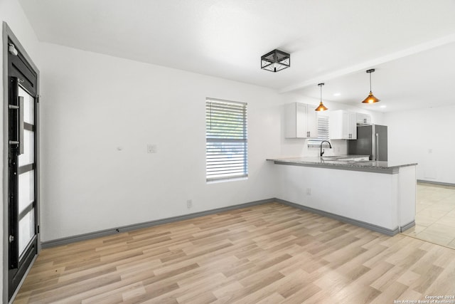 214 Oriole, San Antonio, TX 78228 - kitchen featuring freestanding refrigerator, a peninsula, light wood-style floors, white cabinets, and a sink