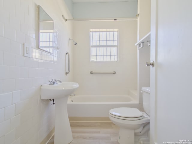 bathroom with shower / bathing tub combination, tile walls, hardwood / wood-style flooring, and toilet