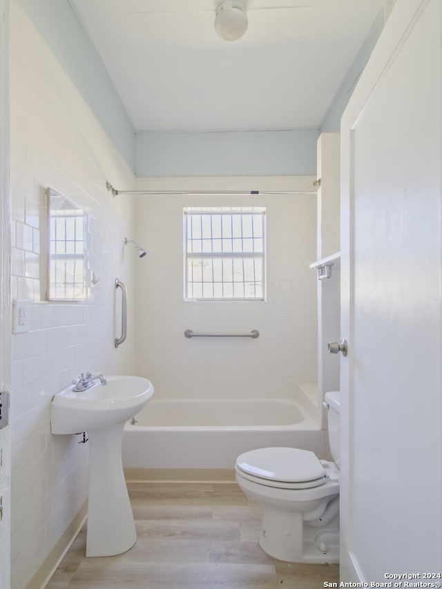 bathroom featuring bathing tub / shower combination, hardwood / wood-style flooring, tile walls, and toilet