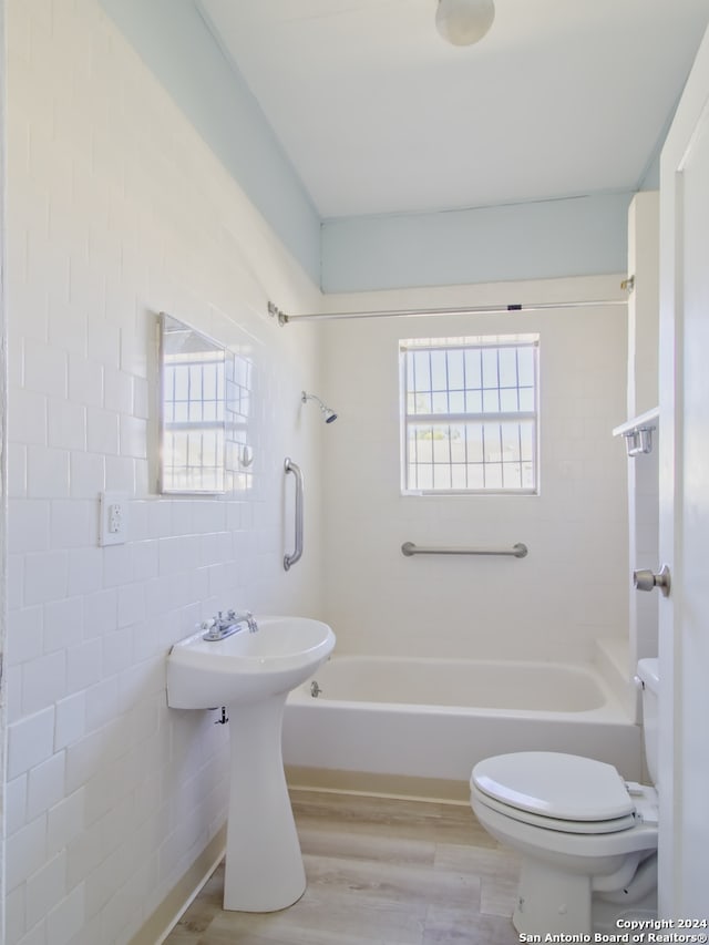 bathroom featuring hardwood / wood-style flooring, tile walls, toilet, and tiled shower / bath combo