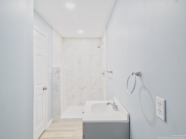 bathroom featuring hardwood / wood-style floors, a tile shower, and vanity