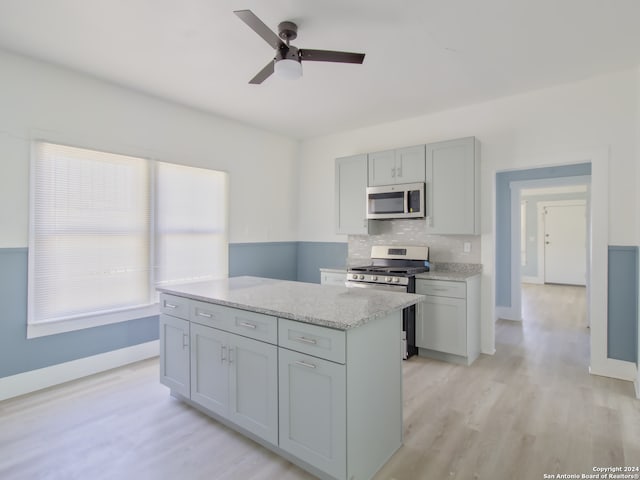 kitchen with ceiling fan, a kitchen island, gray cabinetry, appliances with stainless steel finishes, and light wood-type flooring