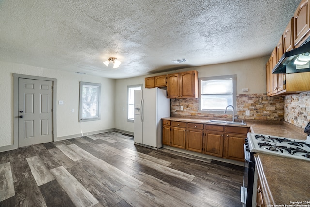 kitchen featuring white appliances, dark hardwood / wood-style floors, sink, and a textured ceiling