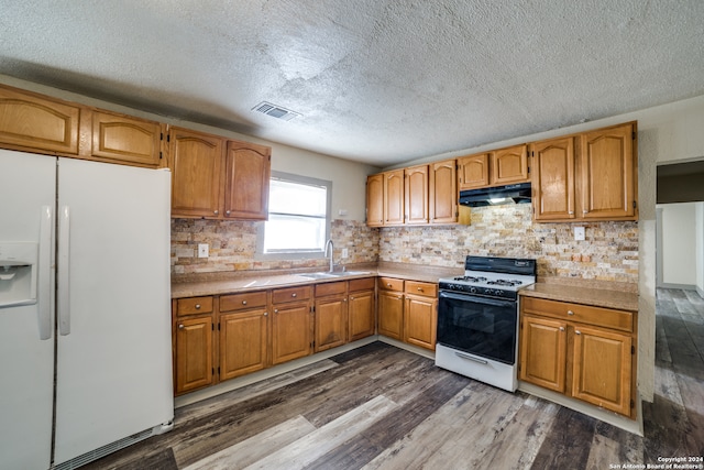 kitchen with white appliances, dark wood-type flooring, sink, decorative backsplash, and a textured ceiling