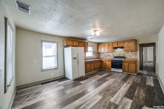 kitchen with a textured ceiling, dark wood-type flooring, and white appliances