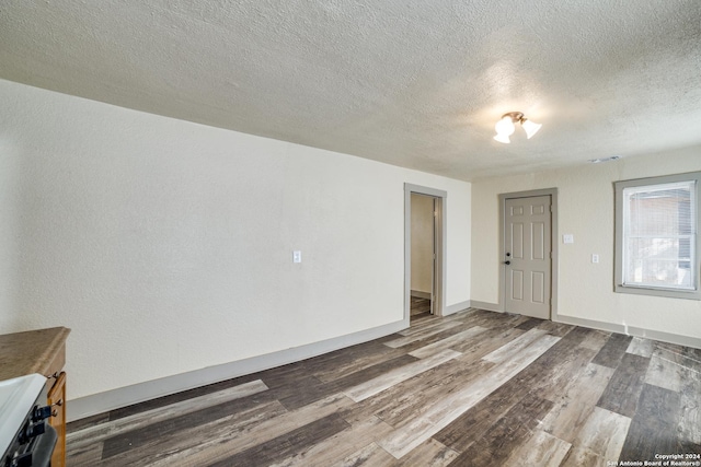 unfurnished living room featuring a textured ceiling, wood finished floors, and baseboards