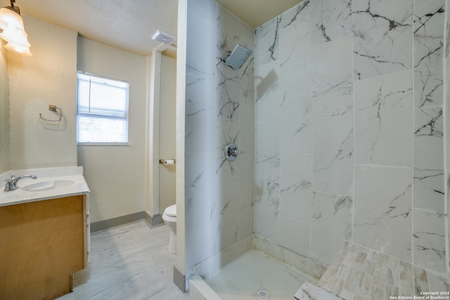 bathroom featuring a tile shower, toilet, and vanity