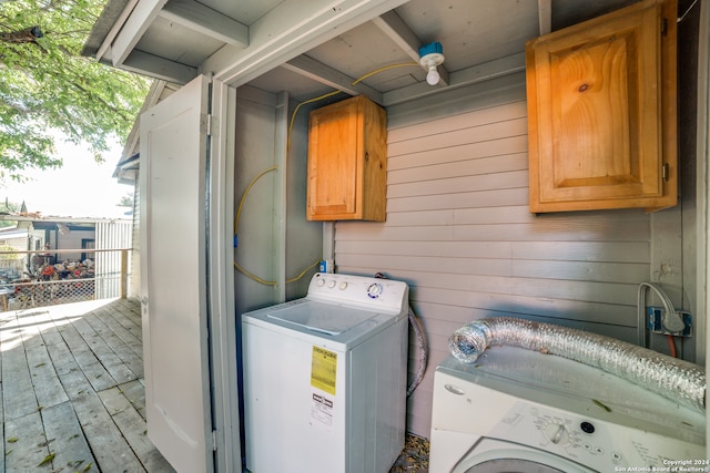 laundry area with cabinets, separate washer and dryer, and wooden walls