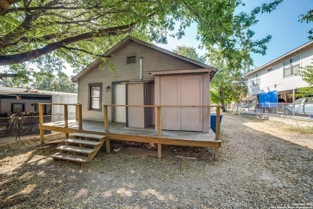 back of house with an outbuilding, a wooden deck, and fence