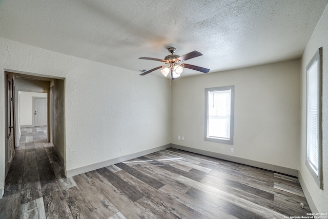 empty room with ceiling fan, a textured ceiling, and dark wood-type flooring