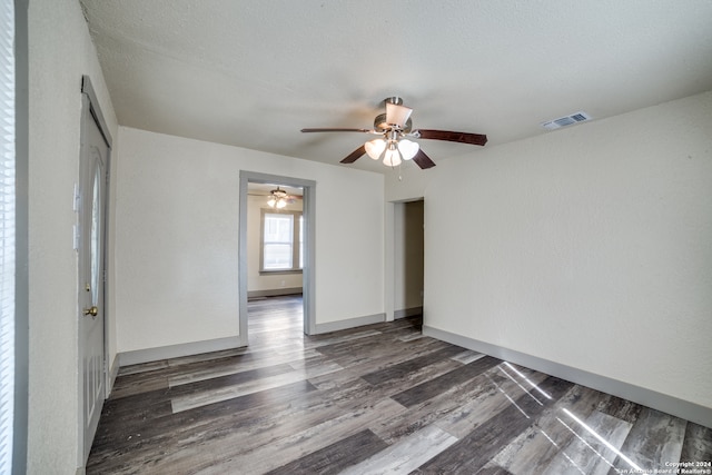 empty room with ceiling fan, dark wood-type flooring, and a textured ceiling