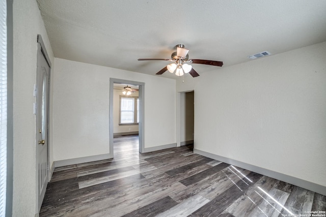 empty room featuring wood finished floors, baseboards, a ceiling fan, and visible vents