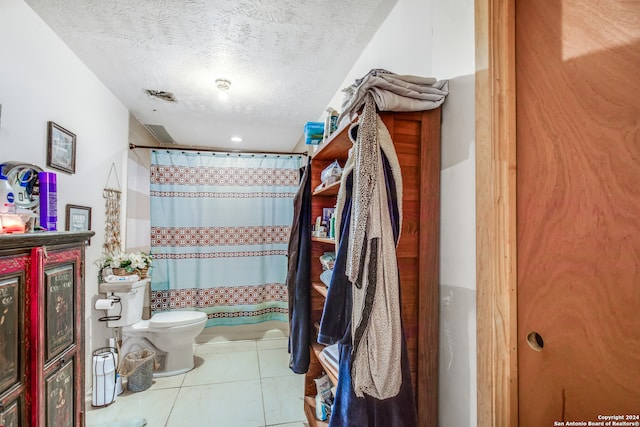 bathroom featuring a shower with shower curtain, a textured ceiling, toilet, and tile patterned floors