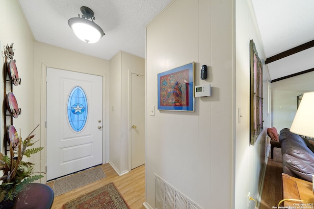 entryway featuring beamed ceiling and light wood-type flooring