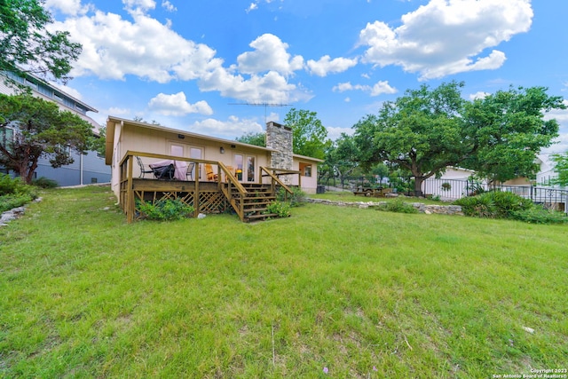 rear view of property with a wooden deck and a lawn