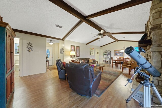 living room featuring light hardwood / wood-style floors, lofted ceiling with beams, and a textured ceiling