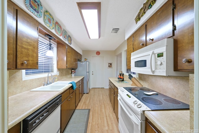 kitchen featuring white appliances, sink, and light wood-type flooring