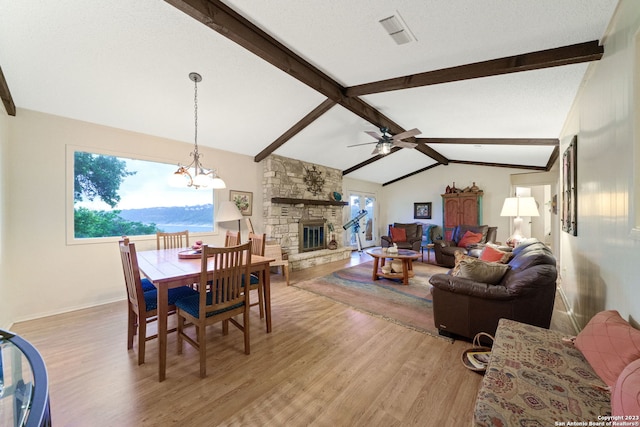 dining space with a stone fireplace, vaulted ceiling with beams, hardwood / wood-style flooring, and a wealth of natural light