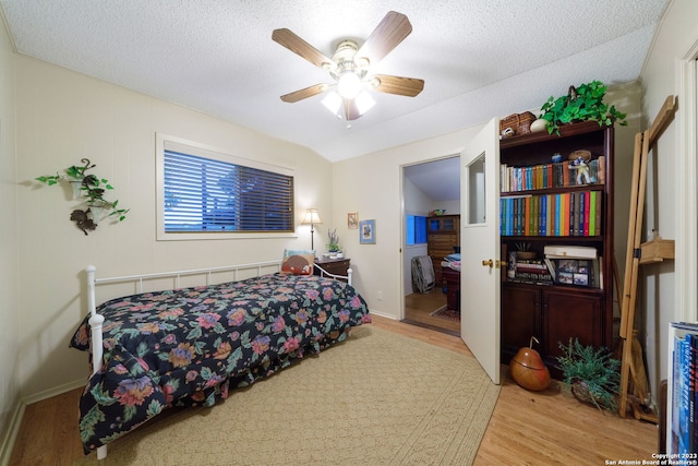 bedroom with ceiling fan, light hardwood / wood-style floors, and a textured ceiling