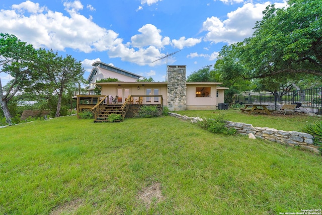 back of house with a wooden deck and a lawn