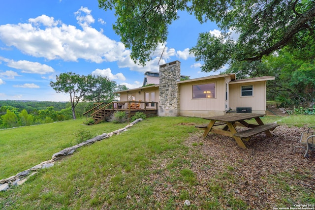 rear view of property featuring a wooden deck and a lawn