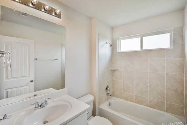 full bathroom featuring tiled shower / bath, vanity, and toilet