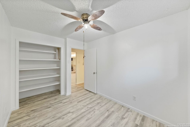 unfurnished bedroom featuring ceiling fan, a textured ceiling, light wood-type flooring, and a closet