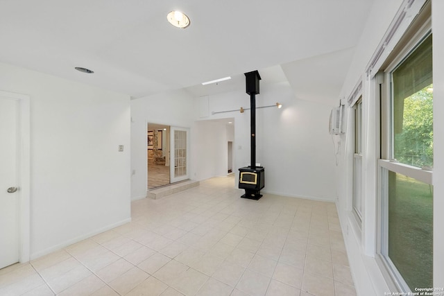 unfurnished living room featuring light tile patterned flooring, an AC wall unit, and a wood stove