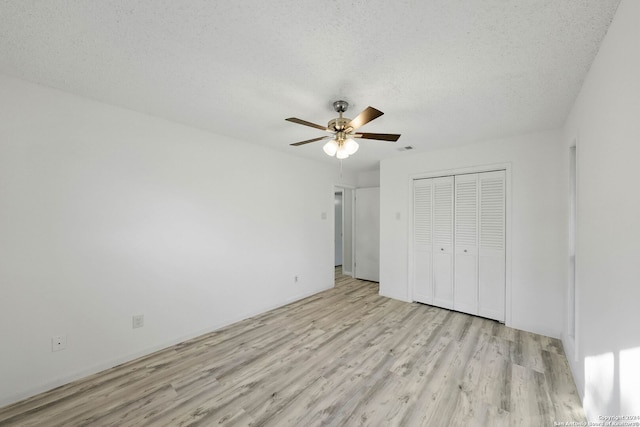 unfurnished bedroom featuring ceiling fan, a textured ceiling, a closet, and light hardwood / wood-style floors