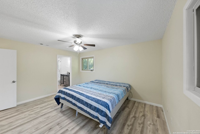 bedroom with connected bathroom, light hardwood / wood-style flooring, a textured ceiling, and ceiling fan