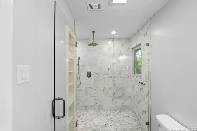 bathroom featuring a textured ceiling, a shower with shower door, and toilet