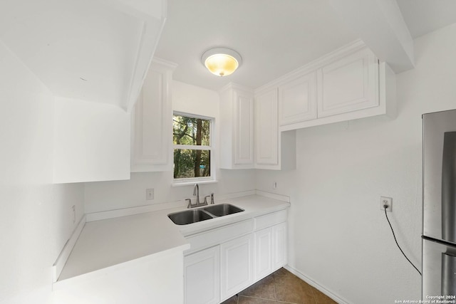 kitchen with sink, dark tile patterned floors, and white cabinetry