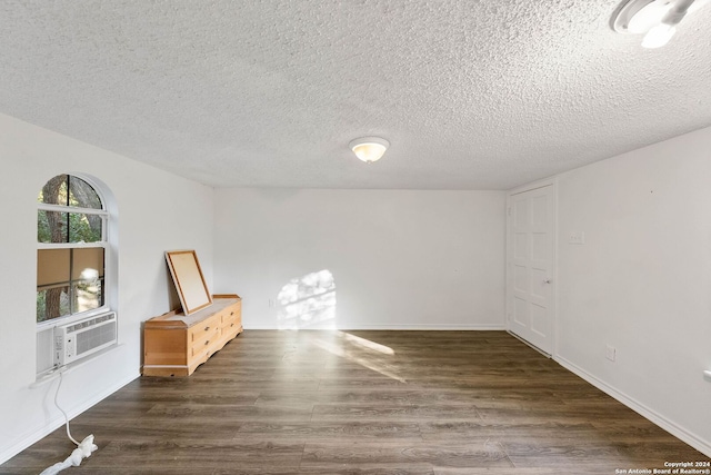 unfurnished room with cooling unit, a textured ceiling, and dark hardwood / wood-style floors