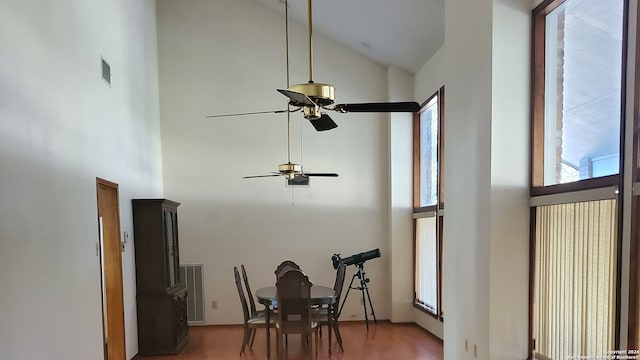 dining space with hardwood / wood-style flooring, high vaulted ceiling, and ceiling fan