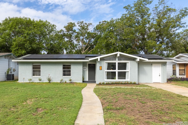 ranch-style home featuring a front yard, central AC unit, and solar panels