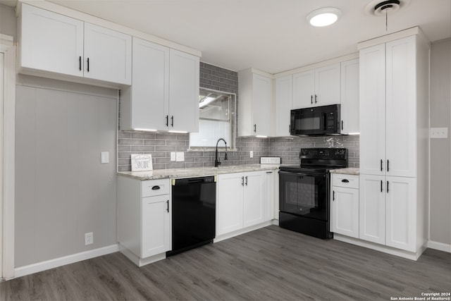 kitchen featuring sink, light stone counters, black appliances, white cabinets, and decorative backsplash