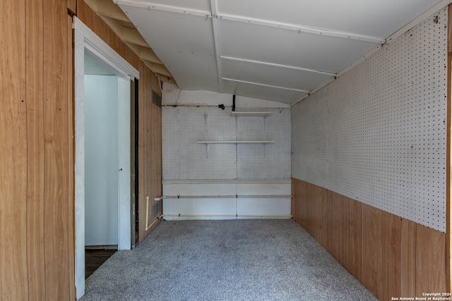 basement featuring dark colored carpet and wood walls