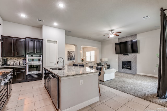 kitchen with ceiling fan, light tile patterned flooring, a center island with sink, and sink