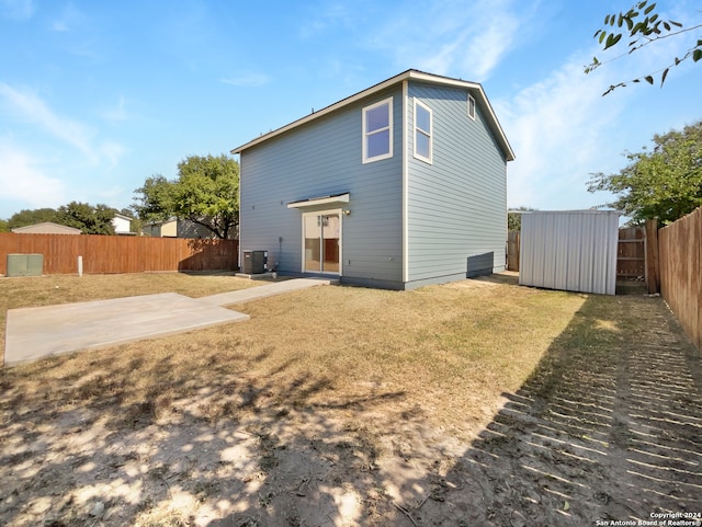 back of property featuring a yard, a shed, a patio, and central AC unit