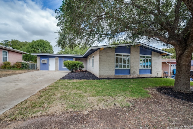 ranch-style house with a wall unit AC, a front yard, and a garage