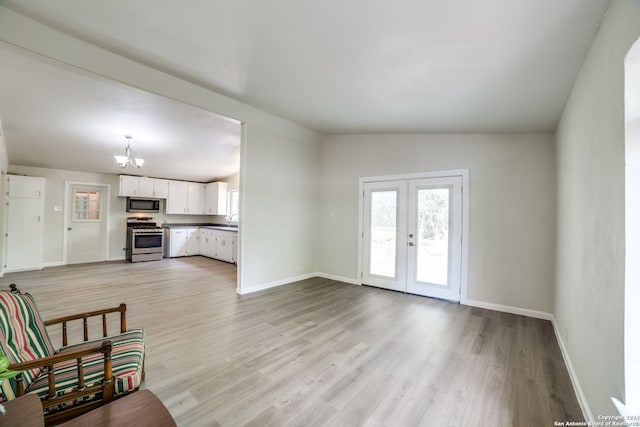 living room with an inviting chandelier, light wood-type flooring, vaulted ceiling, french doors, and sink