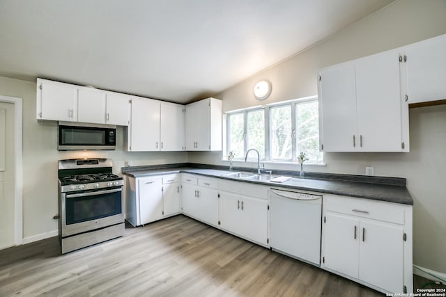 119 Rolling Grn, San Antonio, TX 78228 - kitchen with dark countertops, white cabinets, a sink, light wood finished floors, and appliances with stainless steel finishes