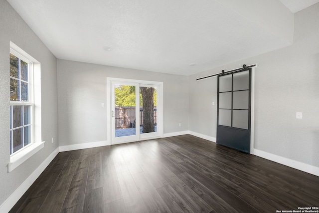 empty room with a barn door and dark hardwood / wood-style flooring