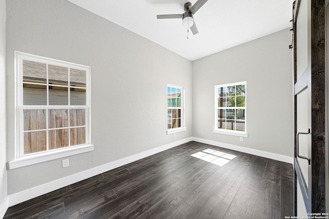 spare room featuring ceiling fan, dark hardwood / wood-style floors, and a barn door