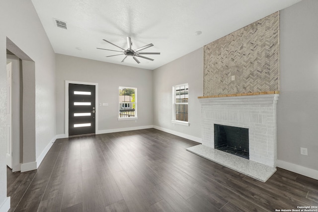 unfurnished living room with a fireplace, dark hardwood / wood-style flooring, and ceiling fan